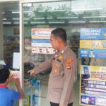 Bhabinkamtibmas Polsek Muara Kuang Tempel Stiker Layanan Polri 110 di Pusat Keramaian
